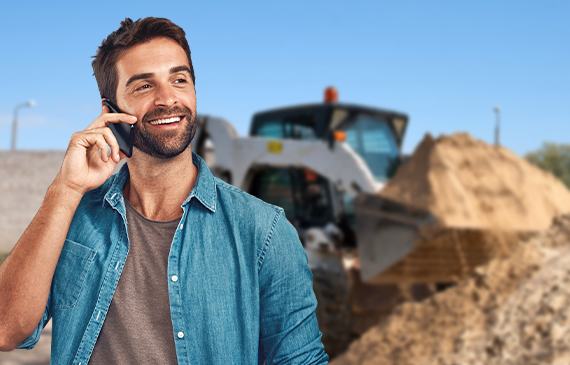 A young male business owner talks on the phone with Beacon Funding's representative about financing a skid steer for their landscaping start-up business.